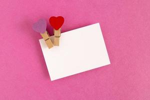 feuille blanche avec des épingles rouges et violettes sur fond rose pour la saint valentin. espace de copie. photo