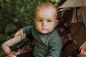 portrait d'un mignon petit garçon tenant une bûche dans le contexte d'une forêt verte. panier de citrouille pour les bonbons au premier plan. marcher et jouer en plein air. notion d'Halloween. photo de haute qualité