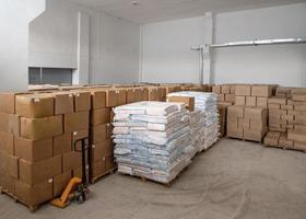 une pile de boîtes et de sacs d'artisanat empilés les uns sur les autres et un chariot mobile dans un entrepôt blanc photo