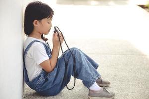 petite fille asiatique priant en tenant la croix, concept chrétien. photo