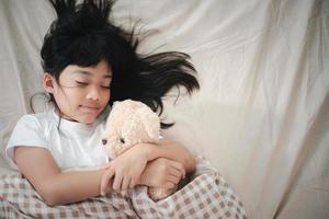 enfant petite fille dort dans le lit avec un ours en peluche photo