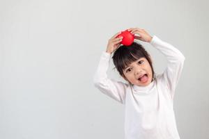 la petite fille en chemise blanche tenant un coeur rouge sur fond blanc. cartes de voeux pour la saint valentin, la fête des mères, la fête des pères. photo