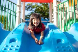 jolie petite fille s'amusant sur une aire de jeux à l'extérieur en été photo