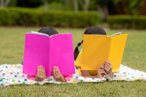 deux belles petites filles lisant des livres dans le jardin, assises sur l'herbe. le concept d'éducation et d'amitié. photo