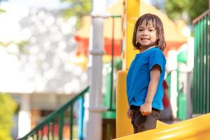 jolie petite fille s'amusant sur une aire de jeux à l'extérieur en été photo