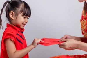 une petite fille asiatique heureuse a reçu une enveloppe rouge de sa mère pour le nouvel an chinois photo