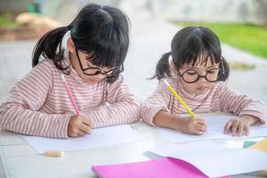 deux enfants asiatiques faisant leurs devoirs ensemble à la maison photo