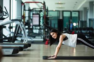 jeune belle fille s'échauffant et faisant des pompes à la salle de sport photo