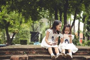 concept enfants et gadgets. deux petites filles frères et sœurs regardent le téléphone et sourient. ils tiennent un smartphone, regardent des vidéos, apprennent, jouent à des jeux, parlent en ligne. Internet pour les enfants. contrôle parental photo