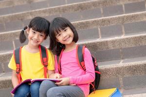 deux petite fille lisant un livre ensemble. adorables enfants asiatiques appréciant d'étudier ensemble à l'extérieur. éducation, concept d'intelligence photo