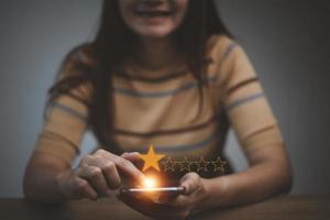 main de femme à l'aide d'un téléphone intelligent et donner le symbole cinq étoiles pour augmenter la note du concept de l'entreprise, l'expérience du service client et l'enquête de satisfaction des entreprises. photo