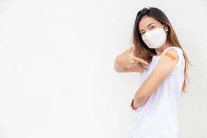 les femmes asiatiques montrent un bandage sur le bras. une femme asiatique heureuse se sent bien après avoir reçu le vaccin sur fond blanc.