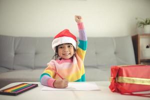 enfant de noël écrire une lettre au père noël, enfant en bonnet de noel écrivant la liste de souhaits photo