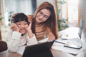 une mère aimante qui soutient sa fille fatiguée étudie ensemble à la maison. maman aidant à réconforter une écolière ayant des difficultés avec l'apprentissage de l'éducation à la maison. photo