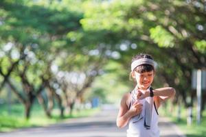 fille enfant heureuse qui court dans le parc en été dans la nature. lumière du soleil chaude. le petit asiatique court dans un parc. sports de plein air et fitness, apprentissage de l'exercice et de la compétition pour le développement des enfants. photo