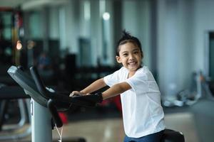 une petite fille utilisant un vélo d'exercice au gymnase. femme de remise en forme à l'aide d'un vélo pneumatique au gymnase. photo
