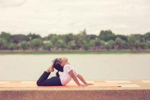 petite fille asiatique mignonne pratiquant la pose de yoga sur un tapis dans le parc, concept de santé et d'exercice photo