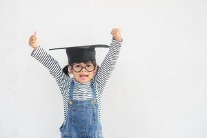 enfants fille portant une casquette de diplômé sur fond blanc très heureux et excité faisant le geste du gagnant avec les bras levés, souriant et criant pour le succès. notion de célébration. photo