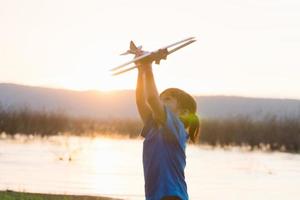 rêves de vol enfant jouant avec un avion jouet contre le ciel au coucher du soleil photo