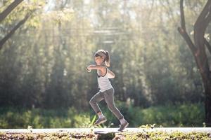 fille enfant heureuse qui court dans le parc en été dans la nature. lumière du soleil chaude. le petit asiatique court dans un parc. sports de plein air et fitness, apprentissage de l'exercice et de la compétition pour le développement des enfants. photo