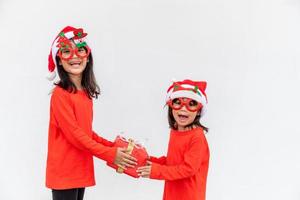 frères et sœurs filles asiatiques en bonnet rouge avec des coffrets cadeaux sur fond blanc. photo