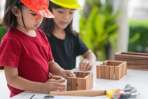 frères et sœurs asiatiques filles portant des chapeaux d'ingénierie construisant une maison à partir du jouet en bois. pour apprendre et améliorer le développement, petit architecte. photo