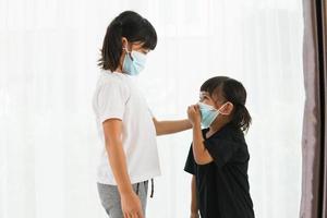 frère petite fille portant un masque pour arrêter l'épidémie de virus corona à la maison.quarantaine frère asiatique.covid-19 coronavirus et symptômes du virus pandémique. photo