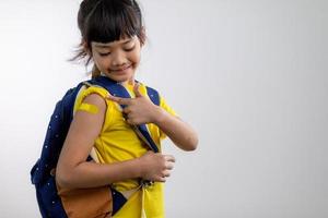 jeune fille asiatique montrant son bras avec un bandage jaune après avoir été vaccinée ou vaccinée, vaccination des enfants, concept de vaccin delta covid photo
