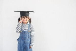 Diplômé d'enfant d'école asiatique heureux pensant avec chapeau de graduation photo