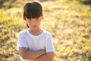 petite fille en colère sur fond de jardin, concept de signe et de geste photo