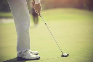 joueur de golf au putting green frapper la balle dans un trou photo