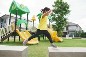 enfant jouant sur une aire de jeux extérieure. les enfants jouent dans la cour de l'école ou de la maternelle. enfant actif sur un toboggan et une balançoire colorés. activité estivale saine pour les enfants. photo