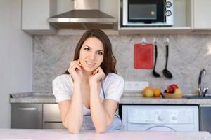 jeune belle femme moderne se tient près de la table dans la cuisine à la maison. mignon souriant. photo