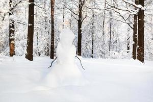 bonhomme de neige sur la clairière de neige dans le parc forestier en hiver photo