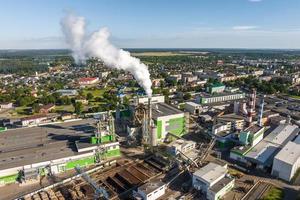 vue panoramique aérienne sur les conduits de fumée d'une usine de menuiserie sur la rive d'une large rivière photo