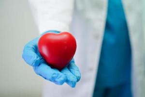 femme médecin asiatique tenant un coeur rouge pour la santé à l'hôpital. photo