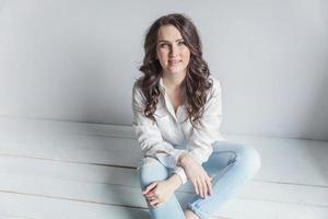 fille dans une pièce lumineuse assise contre un mur blanc photo