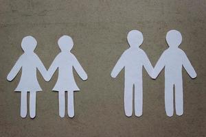deux couples de personnes de même sexe se tenant la main coupant du papier blanc sur beige. un couple de femmes et un couple d'hommes. concept d'amour de même sexe, relation, identité de genre photo