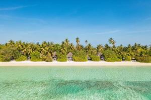 paysage aérien parfait, villas privées de luxe dans un complexe tropical. belle plage de l'île, palmiers, ciel ensoleillé. vue imprenable sur les yeux d'oiseau aux maldives, côte paradisiaque. tourisme exotique, relax nature mer photo