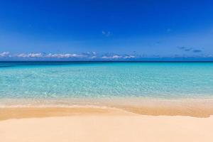 gros plan de sable sur la plage et ciel d'été bleu. paysage de plage panoramique. plage tropicale vide et paysage marin. ciel bleu ensoleillé, sable doux, calme, lumière du soleil relaxante et tranquille, ambiance estivale. rive des vagues photo