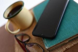 tasses à café jaunes, téléphones et livres sur la table en bois à l'intérieur de la maison. photo