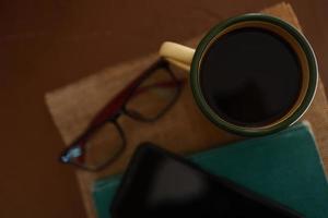 tasses à café jaunes, téléphones et livres sur la table en bois à l'intérieur de la maison. photo