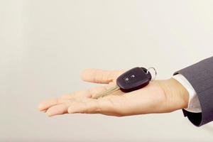 le vendeur porte les clés de voiture livrées au client dans la salle d'exposition avec une offre à faible intérêt. promotion spéciale photo