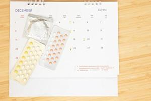 les pilules contraceptives et les préservatifs sur fond de date calendaire calculent la date. contrôler le taux de natalité soins de santé et médecine photo
