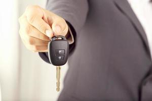 le vendeur porte les clés de voiture livrées au client dans la salle d'exposition avec une offre à faible intérêt. promotion spéciale photo