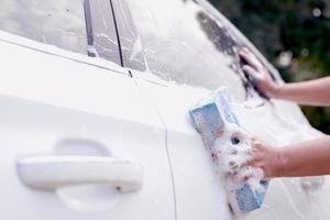 cet homme lave la voiture et nettoie la voiture. photo