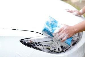 cet homme lave la voiture et nettoie la voiture. photo