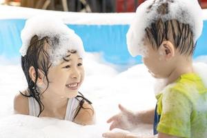 mignons frères et sœurs asiatiques s'amusant dans la piscine. soeur et frère jouant avec des bulles et nageant dans la piscine de vacances d'été. concept de vacances en famille heureuse photo