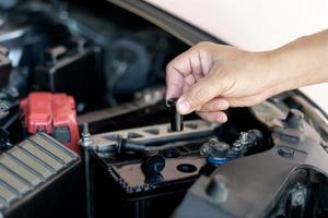 un homme ouvre le capuchon de la batterie d'ajout pour ajouter l'entretien distillé et les inspections pour prolonger la durée de vie de la batterie de la voiture photo