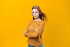 Souriante jeune femme en chandail jaune posant isolé sur jaune pastel photo